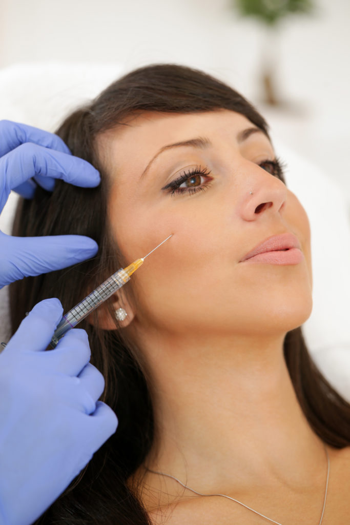 Female doctor injecting dermal fillers into woman's cheek